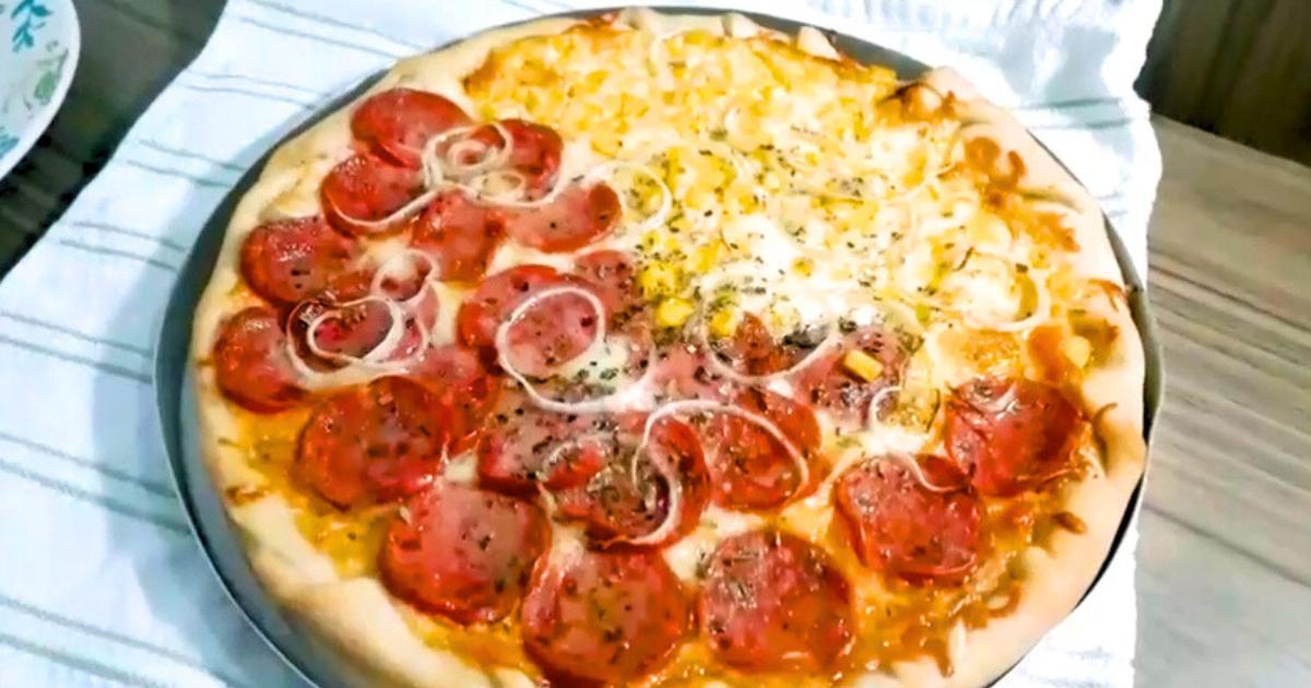 Pizza caseira recém-saída do forno, com borda recheada e cobertura de mussarela, calabresa, cebola e milho.